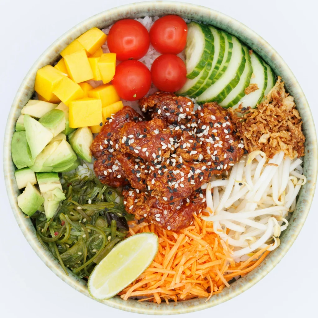 Bol de riz avec tomates, concombre, graines de soja, carottes, mangue